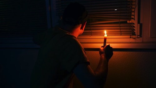 停電の時にロウソクを持って様子を見る男性