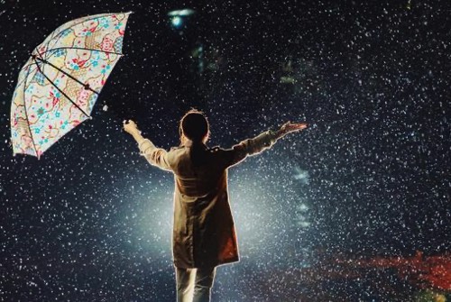 大雨時に手を拡げる女性