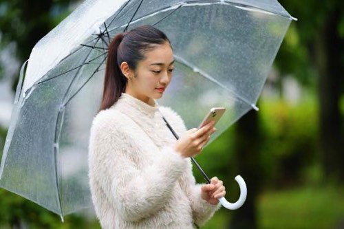 大雨とスマホと女性