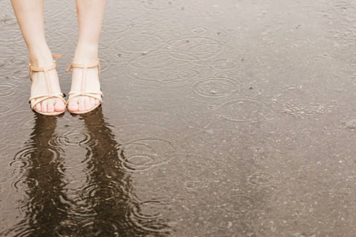 局地的豪雨による大雨時にたたずむ女性の足元