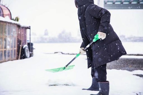 玄関先を除雪する女性