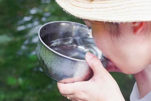 井戸水を汲んで飲む女性