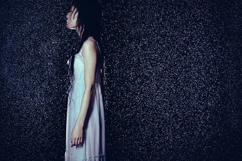 局地的豪雨による大雨時にたたずむ女性を横から