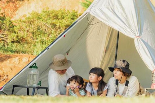 キャンプ中テントの中で寝そべる家族